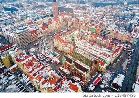 Aerial view of European town covered in snow with red-roofed buildings in winter season. Christmas market and decorated streets Wroclaw city, Poland 119487456