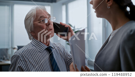 Female financial employee listens to boss communicating with business partner on phone 119488952