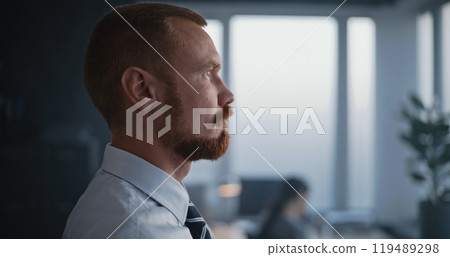 Thoughtful professional banker standing opposite the windows and thinking 119489298