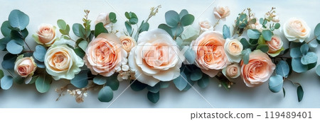 Delicate arrangement of light peach and cream roses with green eucalyptus leaves on a wooden surface 119489401