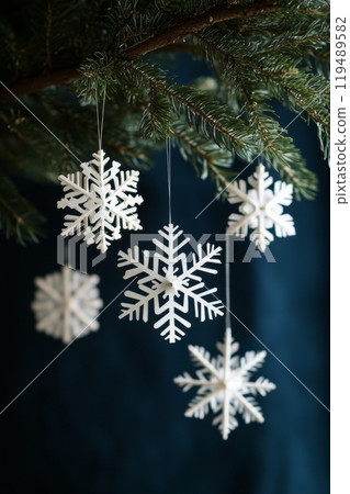 Decorated Christmas tree with white snowflake ornaments against a dark blue backdrop at winter 119489582