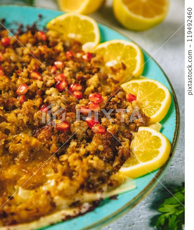 Spicy minced lamb with pomegranate seeds and lemon slices on a plate Spicy minced lamb with pomegranate seeds and lemon slices on a plate 119492460