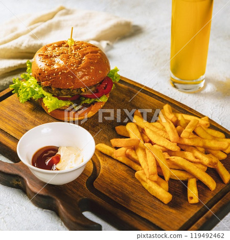 Delicious burger served on wooden board with french fries and dipping sauce Delicious burger served on wooden board with french fries and dipping sauce 119492462