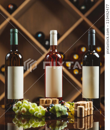 Wine bottles standing with grapes and corks in cellar Wine bottles standing with grapes and corks in cellar 119492477
