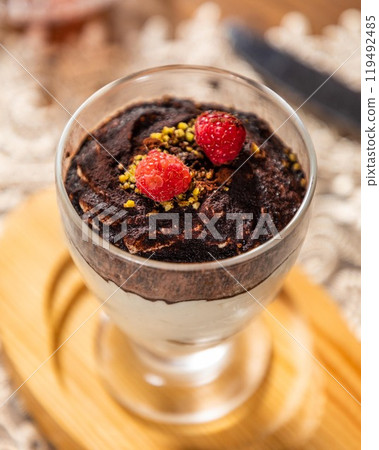 Delicious tiramisu dessert with cocoa powder and raspberries on top Delicious tiramisu dessert with cocoa powder and raspberries on top 119492485