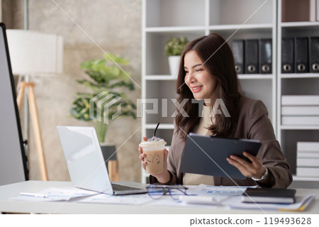 Professional Female Accountant Working on Financial Documents in Modern Office with Laptop and Coffee Professional Female Accountant Working on Financial Documents in Modern Office with Laptop and Coffee 119493628