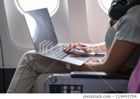 Young Woman Working Online on a Laptop While Traveling on an Airplane, Modern In-Flight Productivity 119493704