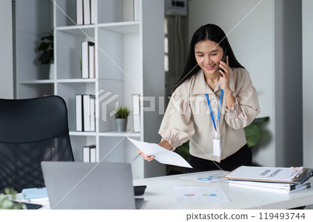 Professional Business Woman Talking on the Phone While Working in a Modern Office Environment Professional Business Woman Talking on the Phone While Working in a Modern Office Environment 119493744