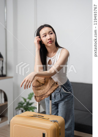 Young Woman Holding a Suitcase in Modern Home Interior, Ready for Travel Adventure, Wearing Casual Summer Outfit Young Woman Holding a Suitcase in Modern Home Interior, Ready for Travel Adventure, Wearing Casual Summer Outfit 119493767