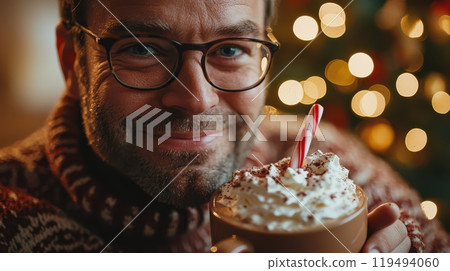 Close-up portrait of a smiling European man enjoying hot chocolate with candy canes, surrounded by festive holiday lights 119494060
