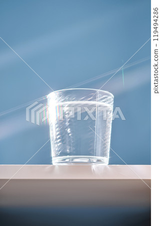 Glass of clean filtered water on blue background with beautiful glare. 119494286