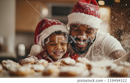 Joyful black father and son baking together wearing Christmas hats during the holiday season in a festive kitchen 119494322