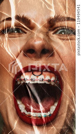 Close-up of woman determined expression, viewed through distorted plastic. Woman emotionally shouting, expressing anger. Conceptual photography. 119494541