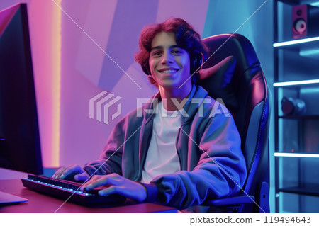 Smiling Teen Gamer in Neon Room 119494643