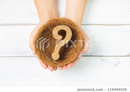 Hands of Inquiry: Wooden Question Mark Safely Held in a Nest by Caring Hands 119494936