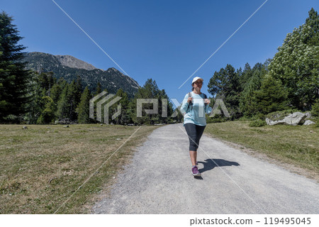 Young pretty tourist woman with backpack walking in a forest road Young pretty tourist woman with backpack walking in a forest road 119495045