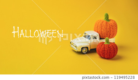 A white truck with two orange pumpkins on the back 119495228