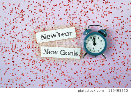 A blue alarm clock sits on a pink background with the words New Year A blue alarm clock sits on a pink background with the words New Year 119495350