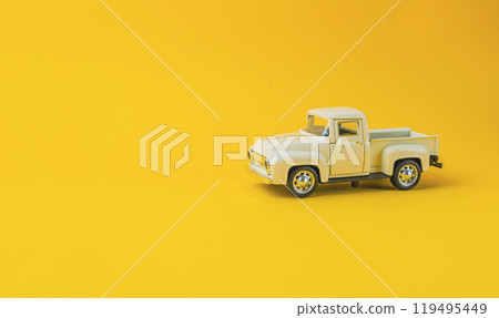 A toy truck is sitting on a yellow background 119495449