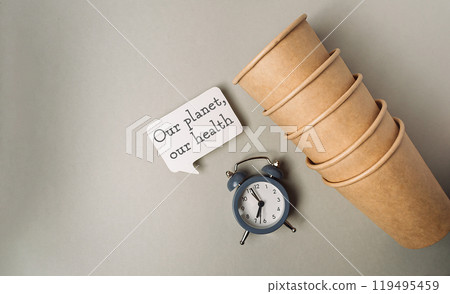 A clock sits on a table next to a stack of paper cups A clock sits on a table next to a stack of paper cups 119495459