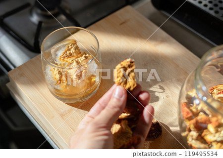 A piece of dried Amanita muscaria mushroom cap held in the hand 119495534