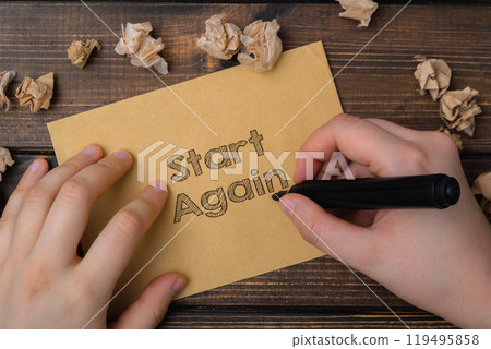 A person is writing the word start again on a piece of paper 119495858
