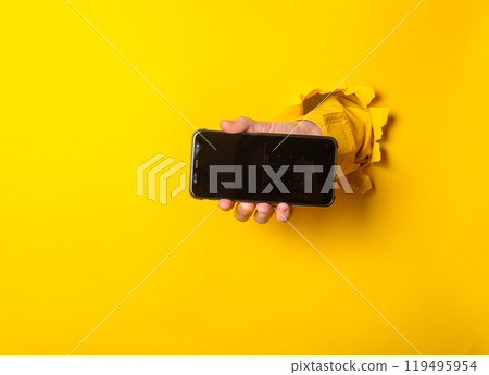 A person holding a phone in front of a yellow background A person holding a phone in front of a yellow background 119495954
