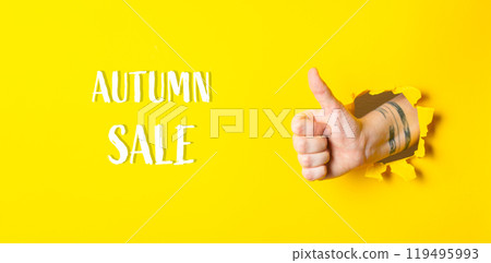Hand is giving a thumbs up in front of a yellow background 119495993