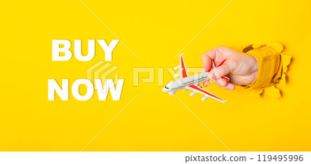 Hand holding a toy airplane with the words Buy Now written underneath Hand holding a toy airplane with the words Buy Now written underneath 119495996