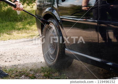 A Close-Up of a Black Car Wheel Being Cleaned with a Pressure Washer A Close-Up of a Black Car Wheel Being Cleaned with a Pressure Washer 119496152