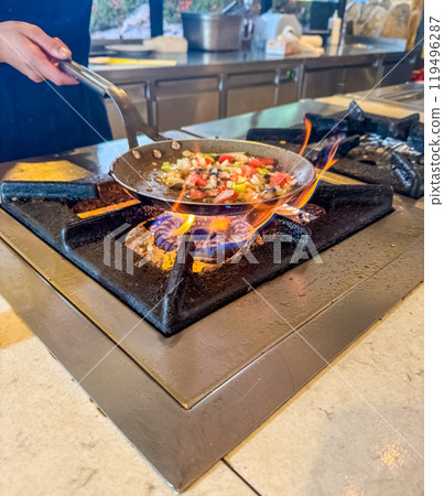Chef cooking vegetables on a gas stove in a kitchen using a saute pan. High quality photo 119496287