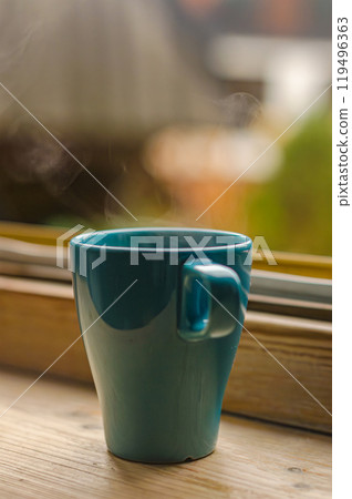 A blue cup of warm tea on wood windowsill . Autumn comfort. Autumn comfort. High quality photo 119496363