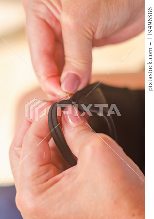 hands of a senior woman who uses needle and thread to repair a black garment. . High quality photo hands of a senior woman who uses needle and thread to repair a black garment. . High quality photo 119496386