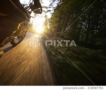 Motorcyclist rides through scenic autumn forest trail. Motorcyclist rides through scenic autumn forest trail. 119497701