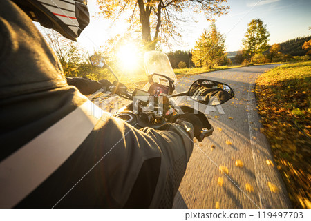 Motorcyclist rides through scenic autumn forest trail. Motorcyclist rides through scenic autumn forest trail. 119497703
