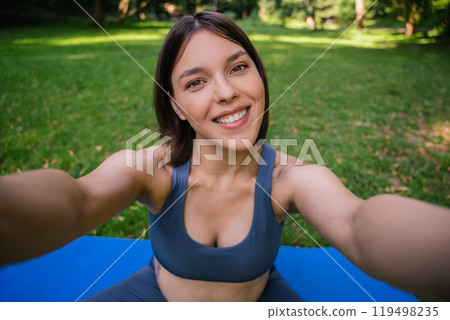 Pregnant woman taking selfie in park during summer yoga training 119498235