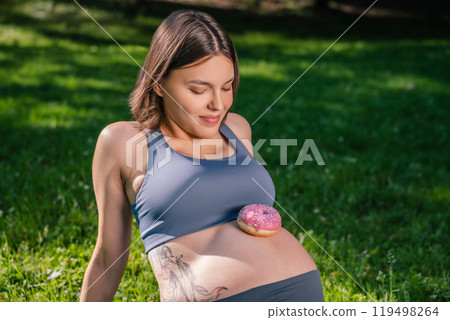 Girl with sugary cake on pregnant belly after physical activity outdoor Girl with sugary cake on pregnant belly after physical activity outdoor 119498264