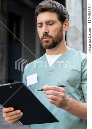 Male doctor writing prescription on clipboard outdoor of medical center Male doctor writing prescription on clipboard outdoor of medical center 119498384