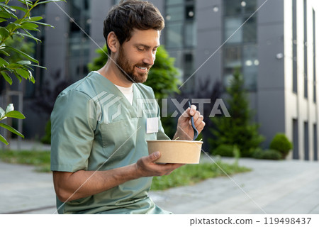 Doctor in scrubs takes lunch break outdoors sitting on bench near medical clinic 119498437