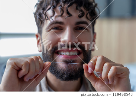Man with dental floss cleaning teeth and braces 119498543