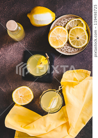 Two glasses of Italian limoncello and lemons on the table top and vertical view Two glasses of Italian limoncello and lemons on the table top and vertical view 119498725
