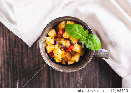 Close up of bread pudding with egg, pepper and basil in a cup on the table top view Close up of bread pudding with egg, pepper and basil in a cup on the table top view 119498733