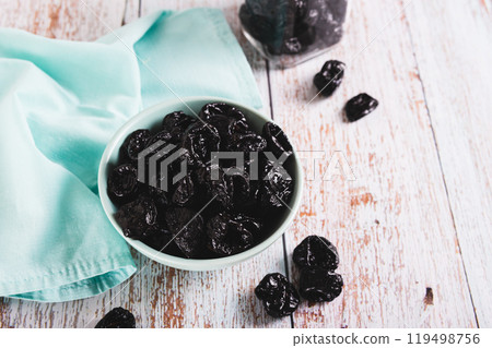Blue bowl with natural organic prunes on table 119498756