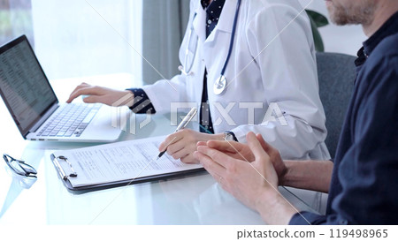 Doctor and patient are talking in clinic after usual health check up. Female physician is making notes and using laptop computer. Medicine concept Doctor and patient are talking in clinic after usual health check up. Female physician is making notes and using laptop computer. Medicine concept 119498965
