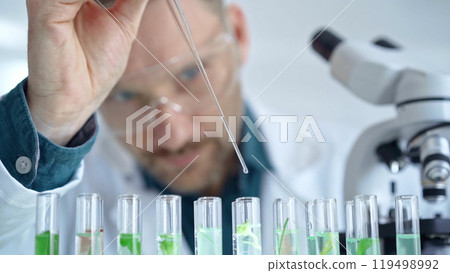 Man researcher with safety glasses is working with lab tubes using a pipette in laboratory, close-up of lab equipment. Science and medicine Man researcher with safety glasses is working with lab tubes using a pipette in laboratory, close-up of lab equipment. Science and medicine 119498992
