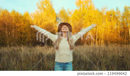 Happy smiling woman in autumn park, joyful girl enjoying warm sunny weather, fall season 119499042