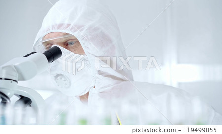 Professional scientist in protective gear is using microscope in a laboratory setting, close-up of researcher. Science and medicine concepts 119499055