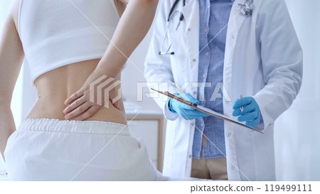 Doctor man wearing blue medical gloves is making notes on a clip 119499111