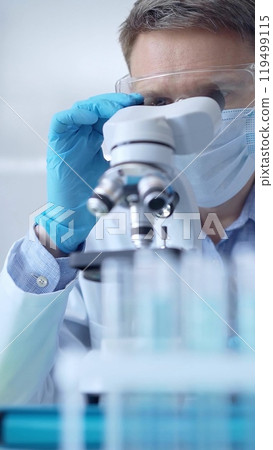 Man scientist with protective glasses, mask and gloves is using 119499115