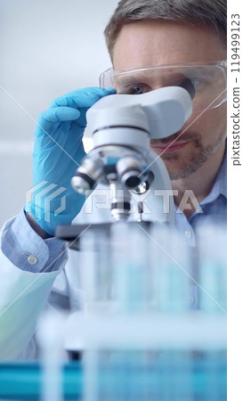 Man scientist with protective glasses and gloves is using micros 119499123
